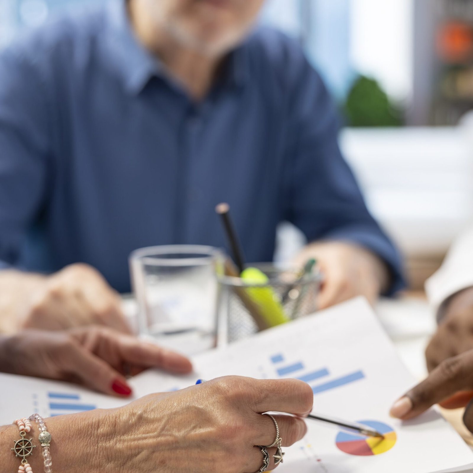 Elderly clients in a modern office meeting with a financial expert, looking into various retirement plans and options. Insurance covering life savings and family expenses for the future.